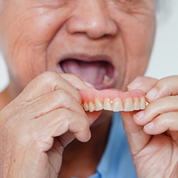 Nose-to-chin view of someone in a blue shirt inserting their top set of dentures