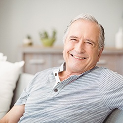 Senior man leaning back against couch and smiling